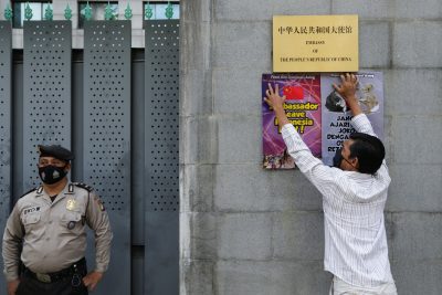 Seorang demonstran memasang poster di luar Kedutaan Besar China setelah adanya laporan bahwa China telah merambah wilayah laut Indonesia di Laut China Selatan, di Jakarta, Indonesia, 8 Desember 2021 (Foto: Reuters/Aging Dinar Ulviana).