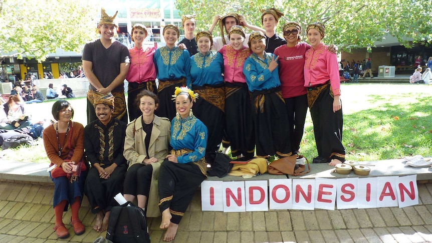 Kata sekelompok orang yang berdiri di luar kampus dengan kertas-kertas mereka dalam bahasa Indonesia