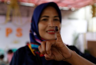 Seorang wanita Indonesia menunjukkan jarinya yang berlumuran tinta setelah memberikan suaranya pada pemilihan kepala daerah di Tangerang, Jakarta Barat, Indonesia, 27 Juni 2018 (Foto: Reuters/Willy Kurniawan).